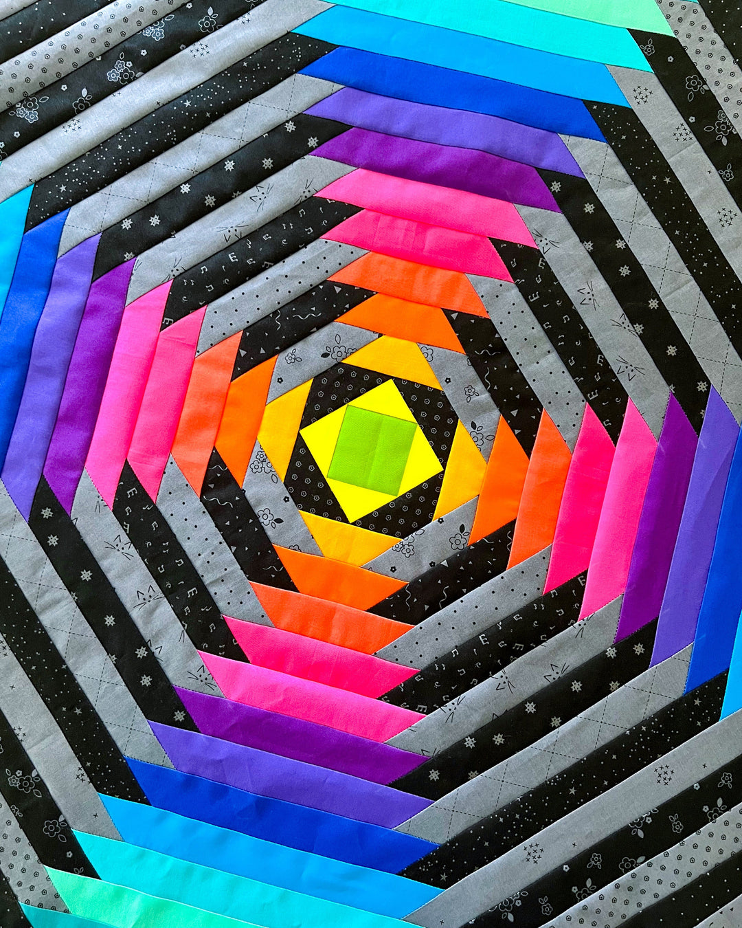 an oversized pineapple block quilt with a rainbow and black and gray fabrics