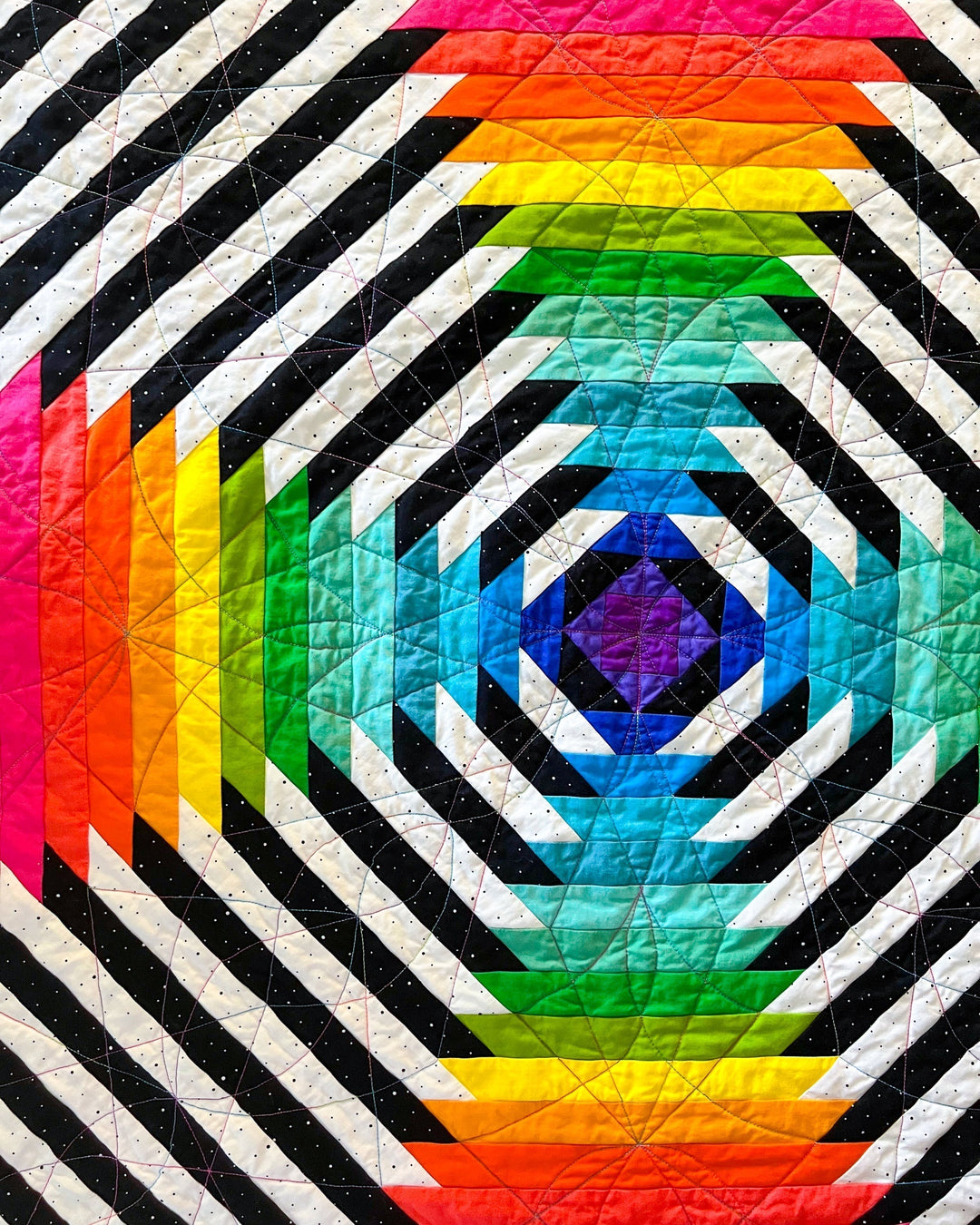 Colorful pineapple quilt with geometric pattern featuring rainbow and black and white stripes.
