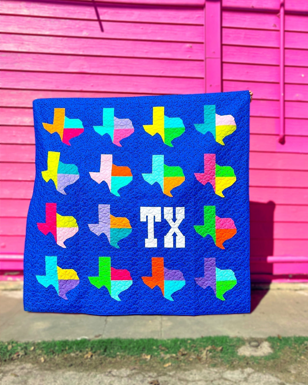 Nothin' Like Texas Quilt Pattern, the cover quilt held against a pink wall