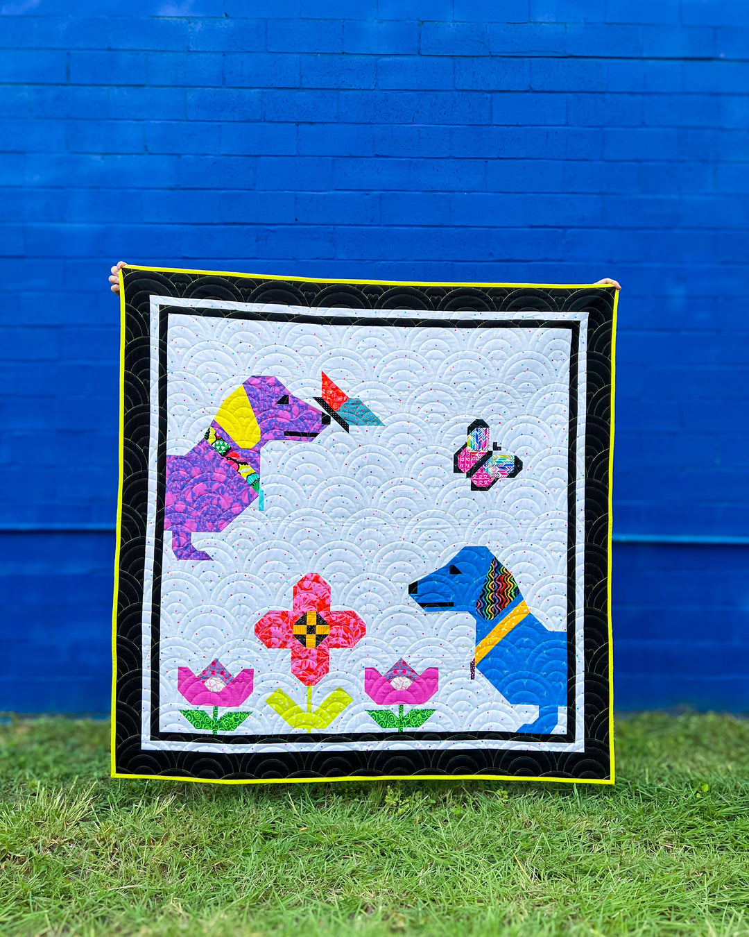 Curious Pups Quilt Sample with Scrappy Fabric Selection against a blue wall