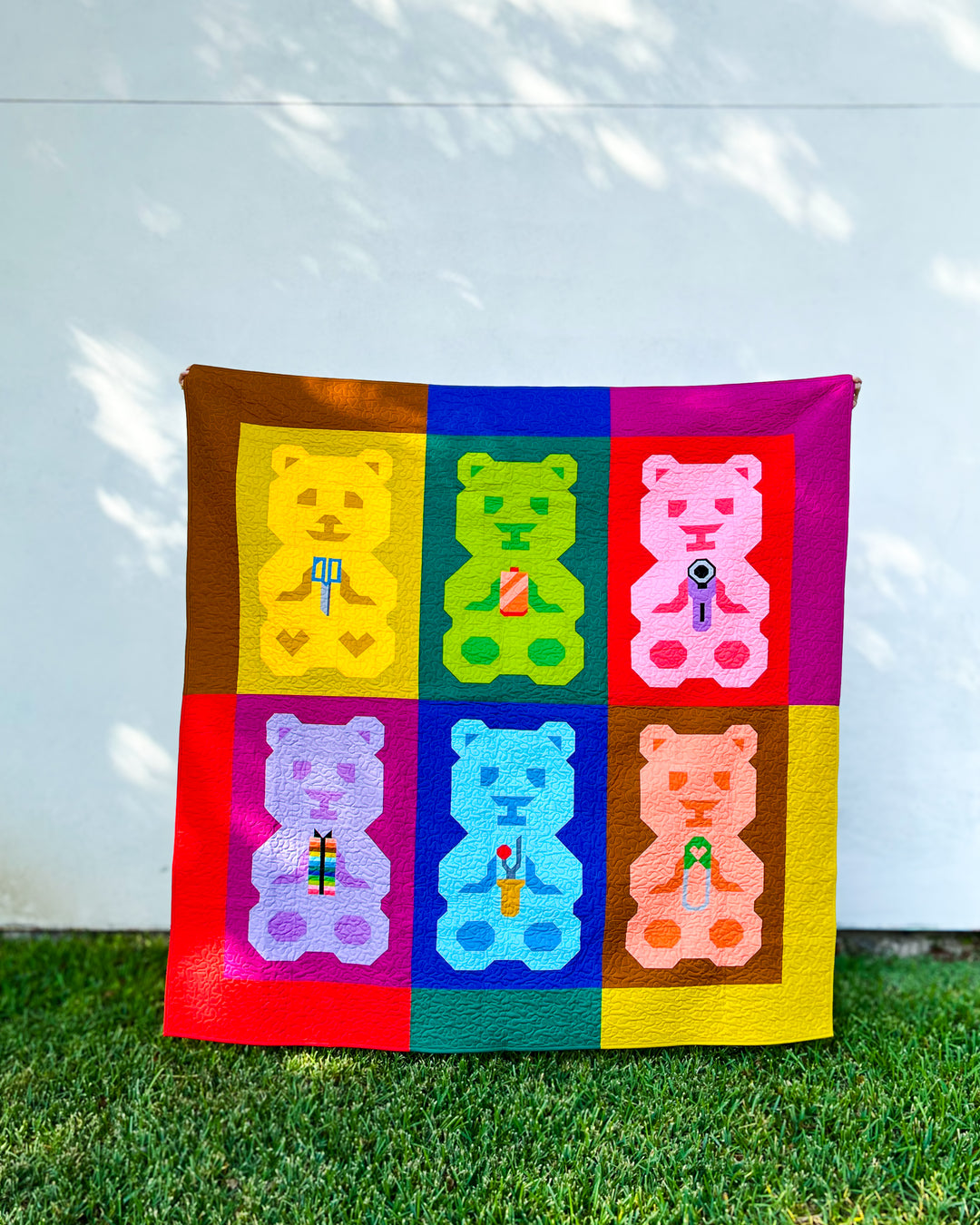 A colorful quilted blanket featuring six teddy bears named &