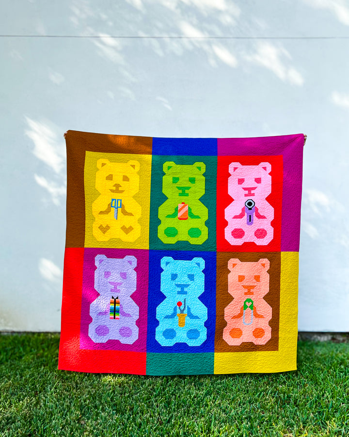 A colorful quilted blanket featuring six teddy bears named &