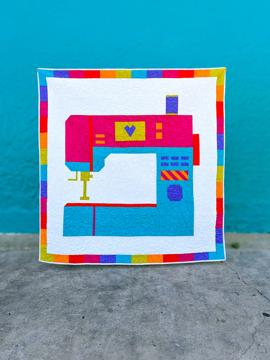 Oh The Possibilities a colorful quilt with a sewing machine design on a blue background