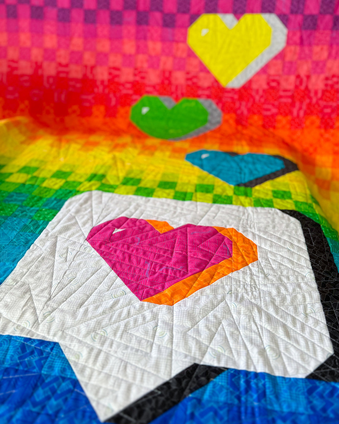 The Send with Love Quilt Pattern is a colorful quilt with heart shapes on a checkered background
