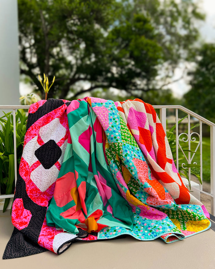 4 versions of the Smashing Petals Quilt draped over an iron staircase railing